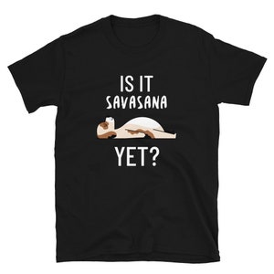 May include: Black t-shirt with white text that reads "Is it Savasana yet?" and a cartoon illustration of a person in the Savasana yoga pose.