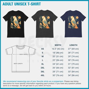 May include: A unisex t-shirt featuring a colourful illustration of a cockatoo bird with flowers. The shirt is available in black, heather grey, and navy blue. The size chart shows the width and length of the shirt in inches and centimetres.