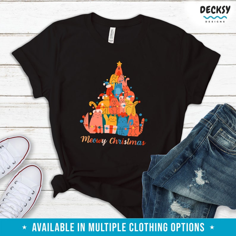 May include: Black t-shirt with a Christmas tree design made of cats. The cats are wearing festive hats and ornaments. The text "Meowy Christmas" is printed below the tree.