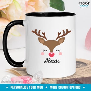 Op de afbeelding: Witte keramische mok met een zwarte rand. De mok heeft een cartoon rendiergezicht met gesloten ogen en een rode neus. De naam "Alexis" staat onder het rendiergezicht gedrukt.
