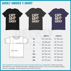 May include: A unisex t-shirt with a black, dark grey, and navy blue color scheme. The shirt features a graphic of a capybara wearing a cowboy hat with the text "CAPY GO LUCKY". The shirt is available in sizes XS to 4XL. The size chart shows the width and length of the shirt in inches and centimeters.