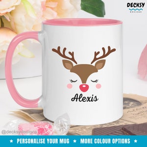 Op de afbeelding: Witte keramische mok met een roze rand en handvat. De mok heeft een cartoon rendiergezicht met gesloten ogen en een rode neus. De naam "Alexis" staat onder het rendier gedrukt.