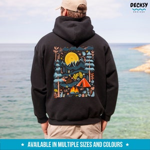 May include: Black hooded sweatshirt with a colorful illustration of a campsite scene with a tent, campfire, and mountains. The illustration is surrounded by a white border.