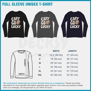 May include: A black, gray, and navy blue long-sleeved t-shirt with a cartoon capybara wearing a cowboy hat and the text "Capy Go Lucky". The t-shirt is available in sizes XS to 2XL. The size chart shows the width and length of the shirt in inches and centimeters.