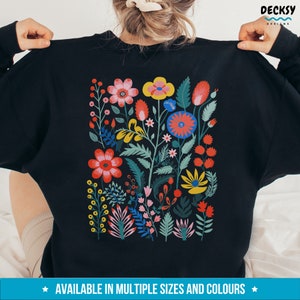 May include: Black sweatshirt with a colorful floral design printed on the back. The design features a variety of flowers in shades of red, pink, yellow, blue, and green.