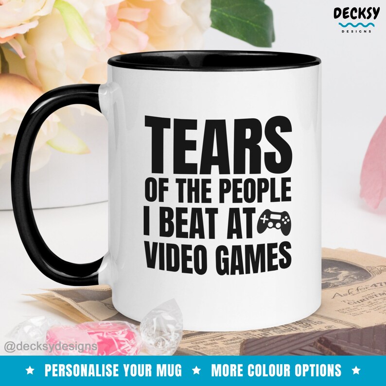 May include: White ceramic mug with a black rim and handle. The mug has black text that reads "Tears of the people I beat at video games" with a video game controller icon.