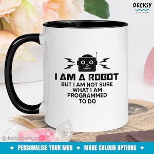 Könnte beinhalten: Eine weiße Kaffeetasse mit schwarzem Rand und Henkel. Die Tasse zeigt eine schwarz-weiße Illustration eines Roboters mit dem Text "Ich bin ein Roboter, aber ich bin mir nicht sicher, was ich programmiert bin zu tun".