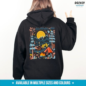 May include: Black hooded sweatshirt with a colorful illustration of a campsite scene on the back. The illustration features a tent, a campfire, mountains, trees, and a bright yellow sun.