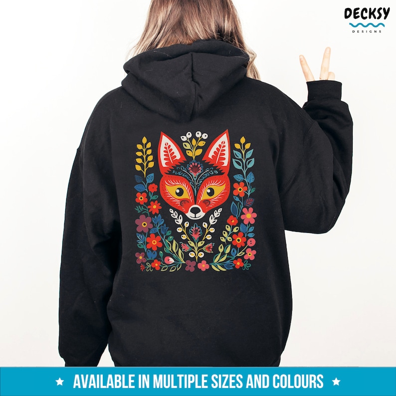 K&ouml;nnte beinhalten: Schwarzer Hoodie mit einem bunten Fuchs-Design auf der R&uuml;ckseite. Der Fuchs ist von Blumen und Bl&auml;ttern im Folk-Art-Stil umgeben.