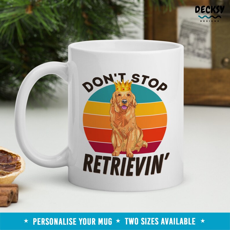 K&ouml;nnte beinhalten: Wei&szlig;e Keramiktasse mit einem Golden Retriever, der eine Krone tr&auml;gt und den Text "Don't Stop Retrievin'" in einer Retro-Schriftart. Der Hintergrund ist ein kreisf&ouml;rmiger Sonnenuntergang mit Streifen.