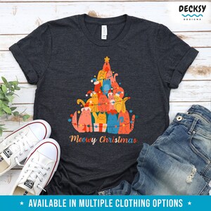 May include: A dark heather grey t-shirt with a Christmas tree design featuring a stack of cats wearing Santa hats and surrounded by Christmas lights. The text "Meowy Christmas" is printed below the tree.