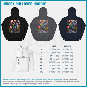 May include: A unisex pullover hoodie with a floral print in shades of pink, red, yellow, green, and blue. The hoodie is available in black, gray, and navy blue. The size chart shows the width and length of the hoodie in inches and centimeters.