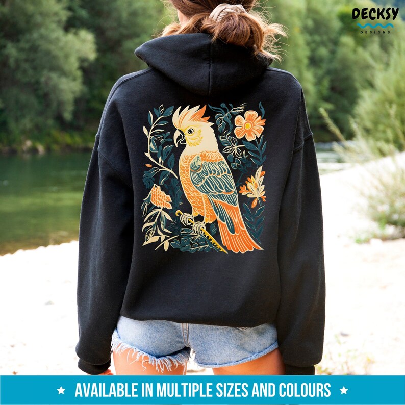May include: Black hooded sweatshirt with a colourful illustration of a cockatoo bird surrounded by flowers and leaves on the back.
