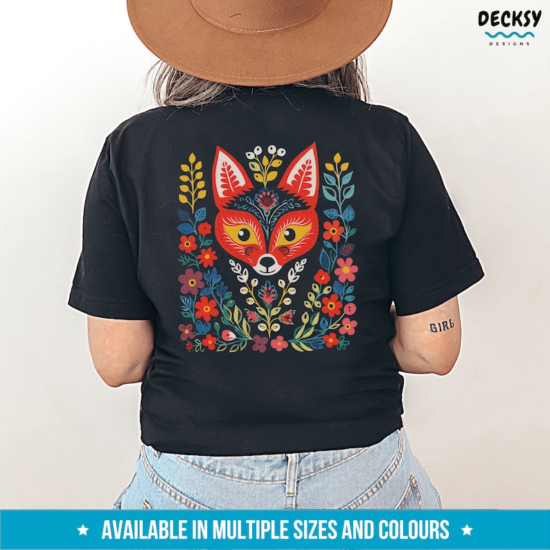 K&ouml;nnte beinhalten: Schwarzes T-Shirt mit einem bunten Fuchs-Design auf der R&uuml;ckseite. Der Fuchs ist von Blumen und Bl&auml;ttern umgeben. Das Design ist im Stil der Volkskunst.