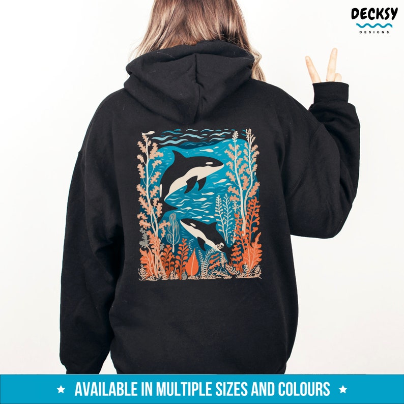 May include: Black hoodie with a graphic print of two orcas swimming in a blue ocean with coral and seaweed. The graphic is in a retro style with orange, blue, and white colors.