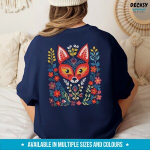 K&ouml;nnte beinhalten: Ein marineblaues Sweatshirt mit einem farbenfrohen Fuchs-Design. Der Fuchs ist von Blumen und Bl&auml;ttern im Volksstilstil umgeben. Das Sweatshirt ist in verschiedenen Gr&ouml;&szlig;en und Farben erh&auml;ltlich.