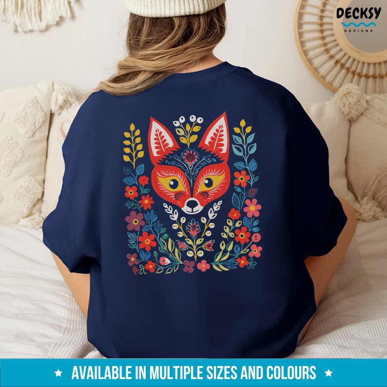 K&ouml;nnte beinhalten: Ein marineblaues Sweatshirt mit einem farbenfrohen Fuchs-Design. Der Fuchs ist von Blumen und Bl&auml;ttern im Volksstilstil umgeben. Das Sweatshirt ist in verschiedenen Gr&ouml;&szlig;en und Farben erh&auml;ltlich.