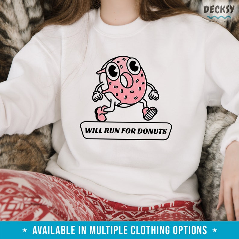 Puede incluir: Sudadera blanca con un dibujo animado de donut rosa corriendo y el texto "WILL RUN FOR DONUTS".
