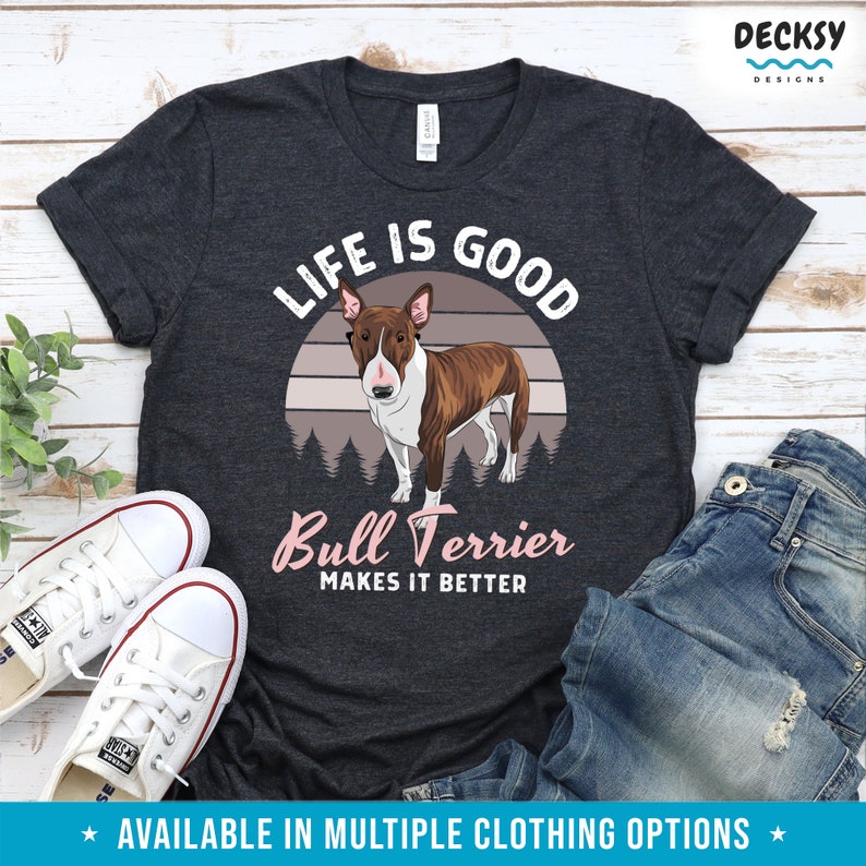 May include: A dark gray t-shirt with a white and pink graphic design. The graphic features a brown and white bull terrier dog standing in front of a sunset with the text "Life is Good" above the dog and "Bull Terrier Makes it Better" below the dog.