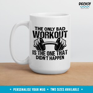 May include: White ceramic mug with a black graphic that reads "The only bad workout is the one that didn't happen." The graphic also features a black dumbbell.