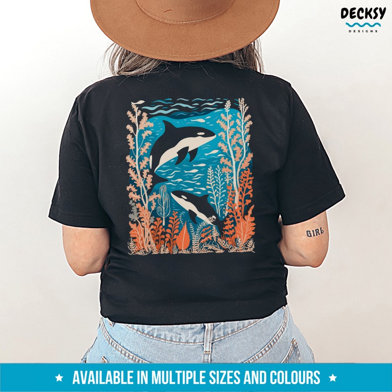 May include: Black t-shirt with a graphic of two orcas swimming in a coral reef. The graphic is in shades of blue, orange, and green. The text "Girl" is printed on the right sleeve.