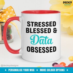 May include: White ceramic mug with a red rim. The mug has a black and teal design that says "Stressed Blessed & Data Obsessed".
