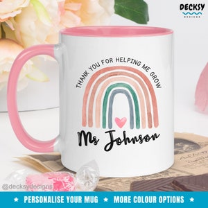 May include: White ceramic mug with a pink rim and handle. The mug features a watercolor rainbow with a pink heart in the center and the text "Thank you for helping me grow" and "Ms. Johnson".