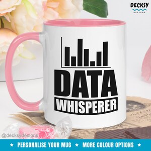 May include: White ceramic mug with a pink rim and handle. The mug has a black graphic of a bar chart and the text "DATA WHISPERER".