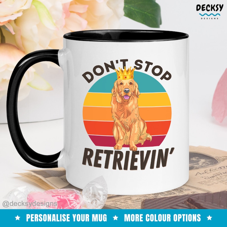 K&ouml;nnte beinhalten: Wei&szlig;e Keramiktasse mit schwarzem Rand und Henkel. Die Tasse zeigt eine Grafik im Retro-Stil mit einem Sonnenuntergang und einem Golden Retriever, der eine Krone tr&auml;gt. Der Text "Don't Stop Retrievin'" ist auf die Tasse gedruckt.