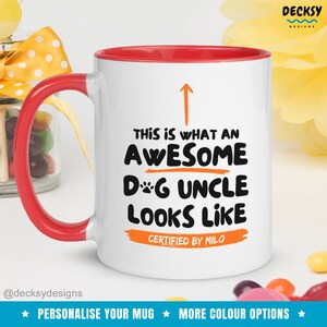 May include: White ceramic mug with a red rim and handle. The mug has a black and orange design that says "This is what an awesome dog uncle looks like. Certified by Milo."