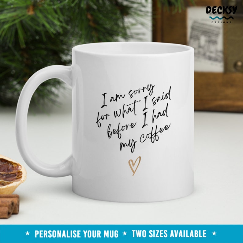 May include: White ceramic coffee mug with black text that reads "I am sorry for what I said before I had my coffee" with a gold heart symbol.