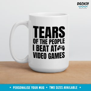 May include: White ceramic mug with a black graphic that reads "Tears of the people I beat at video games" and a black video game controller icon.