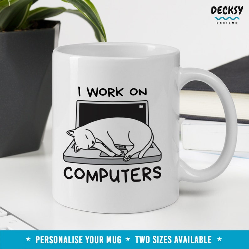 May include: White ceramic mug with a black and white illustration of a cat sleeping on a laptop. The text "I work on computers" is printed on the mug.