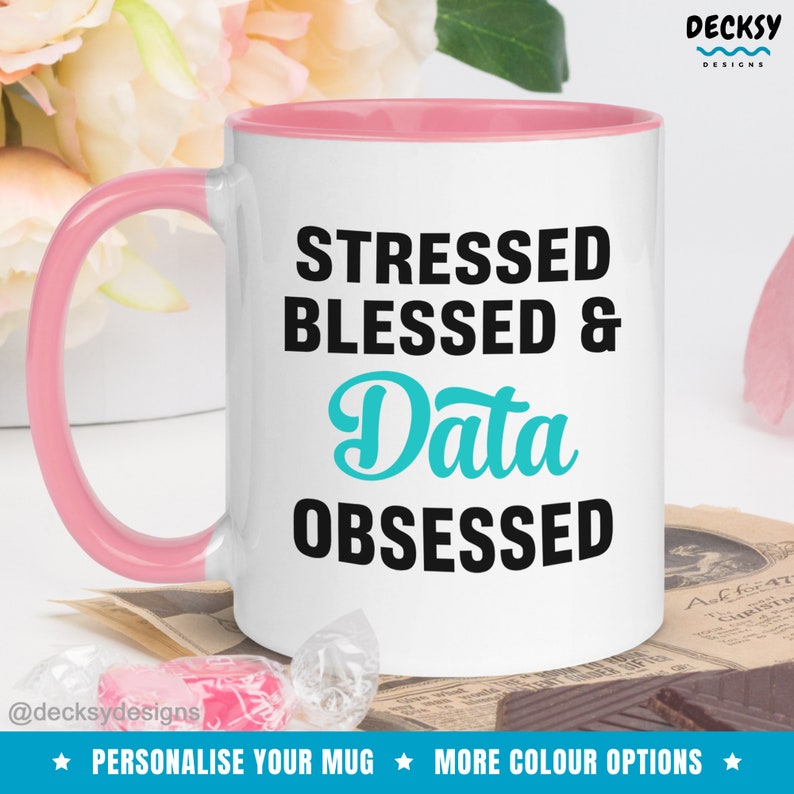 May include: White ceramic mug with a pink rim and handle. The mug has black text that reads "Stressed Blessed & Data Obsessed". The word "Data" is in turquoise.