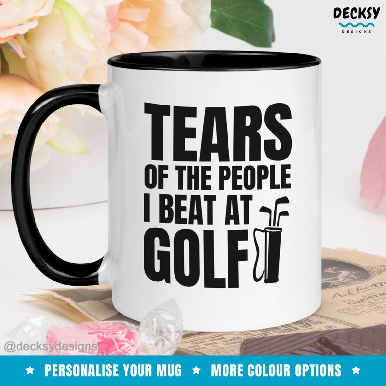 May include: White coffee mug with a black rim and handle. The mug has black text that reads "Tears of the people I beat at golf" with a golf club and bag graphic.