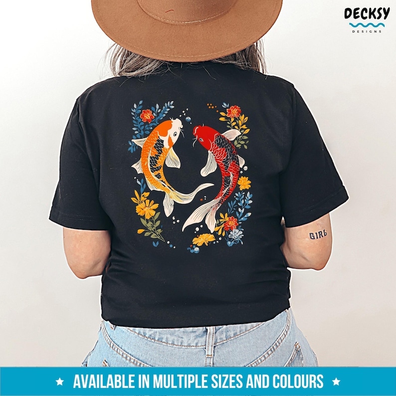 May include: Black t-shirt featuring a graphic of two koi fish swimming in a floral design. The fish are red, orange, and white. The flowers are blue, yellow, and green.