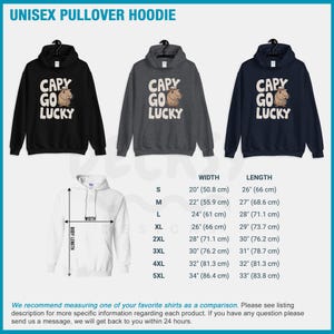 May include: A unisex pullover hoodie with a black, gray, and navy blue color options. The hoodie features a cartoon capybara wearing a cowboy hat and the text "Capy Go Lucky". The size chart is shown in inches and centimeters.