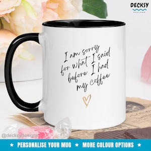 May include: White coffee mug with a black rim and handle. The mug has black text that reads "I am sorry for what I said before I had my coffee" with a gold heart below the text.
