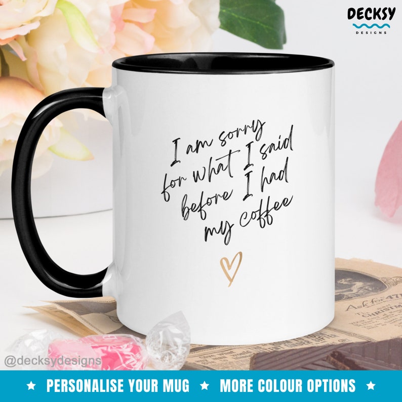 May include: White coffee mug with a black rim and handle. The mug has black text that reads "I am sorry for what I said before I had my coffee" with a gold heart below the text.