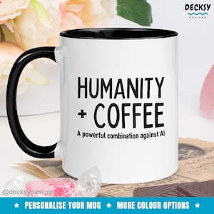 Puede incluir: Taza de café blanca con borde y asa negros. La taza tiene texto negro que dice "HUMANITY + COFFEE A powerful combination against AI".