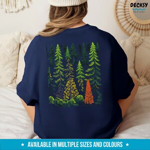 May include: A navy blue sweatshirt with a graphic of a forest scene. The trees are outlined in green, yellow, and orange. The design is centered on the back of the sweatshirt.