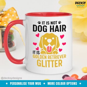 May include: White ceramic mug with a red rim. The mug features a golden retriever dog with a pink tongue sticking out. The text on the mug reads "It is not dog hair, it is golden retriever glitter".