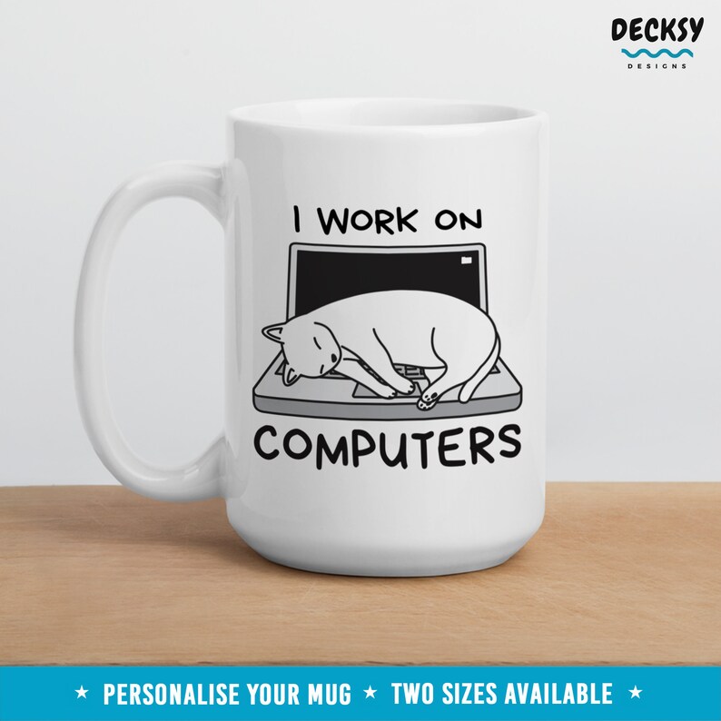 May include: White ceramic mug with a black and white illustration of a cat sleeping on a laptop. The text "I work on computers" is printed on the mug.