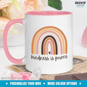 May include: White ceramic mug with a pink rim and handle. The mug features a rainbow design with the text "kindness is power" in brown lettering.