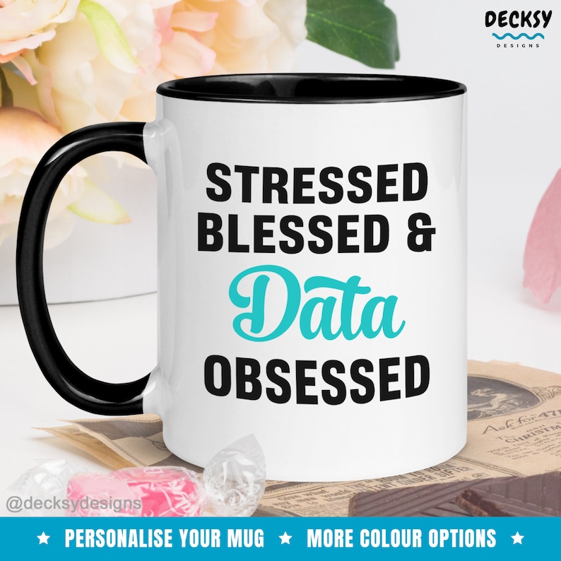 May include: White ceramic mug with a black rim. The mug has a black handle and features the text "STRESSED BLESSED & Data OBSESSED" in black and turquoise lettering.
