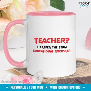 K&ouml;nnte beinhalten: Wei&szlig;e Keramiktasse mit rosafarbenem Rand und Henkel. Die Tasse hat eine rote Grafik mit dem Text "TEACHER? I PREFER THE TERM EDUCATIONAL ROCKSTAR".