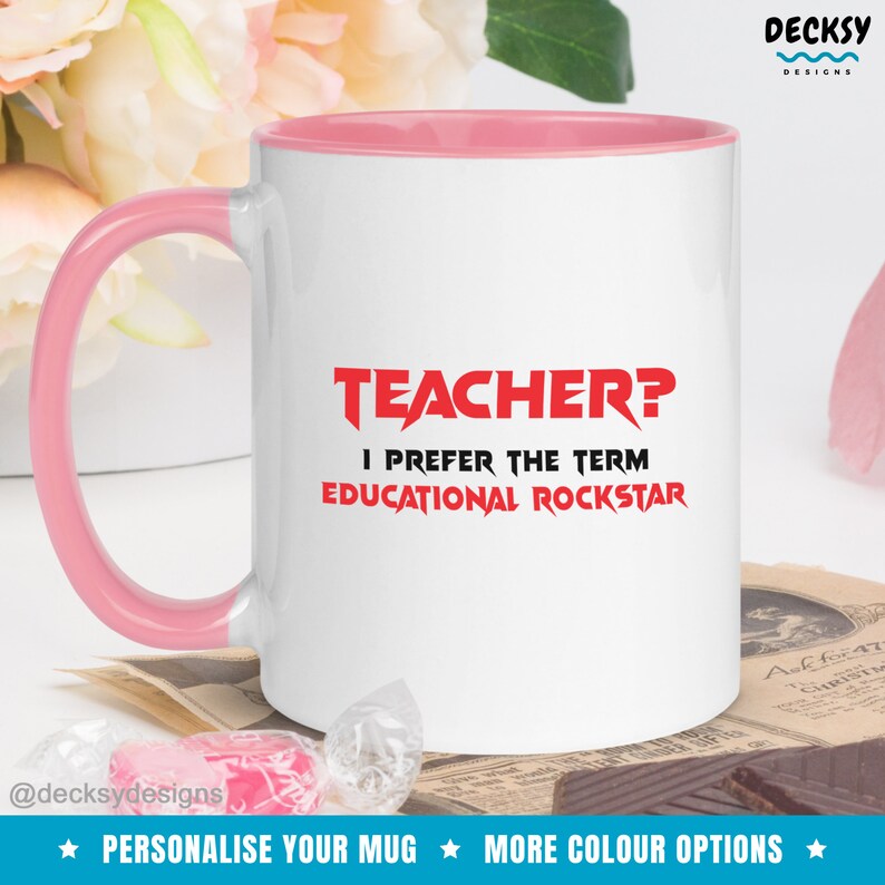 K&ouml;nnte beinhalten: Wei&szlig;e Keramiktasse mit rosafarbenem Rand und Henkel. Die Tasse hat eine rote Grafik mit dem Text "TEACHER? I PREFER THE TERM EDUCATIONAL ROCKSTAR".
