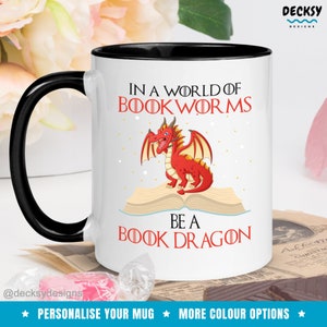May include: White ceramic mug with a black rim and handle. The mug features a red dragon sitting on an open book with the text "In a world of bookworms be a book dragon".