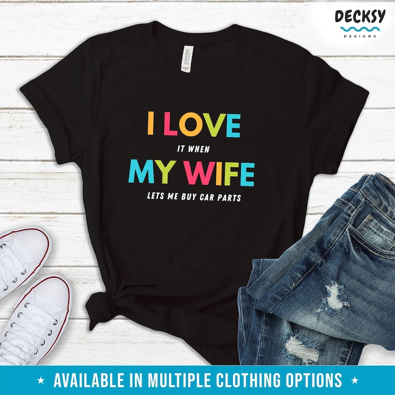 Pu&ograve; includere: T-shirt nero con la scritta "I LOVE it when MY WIFE lets me buy car parts" a lettere colorate. La maglietta &egrave; abbinata a jeans blu e scarpe da ginnastica bianche. La frase "AVAILABLE IN MULTIPLE CLOTHING OPTIONS" &egrave; in basso.