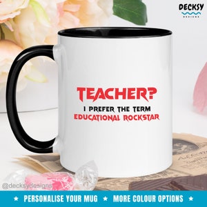 K&ouml;nnte beinhalten: Wei&szlig;e Keramiktasse mit schwarzem Rand und Henkel. Die Tasse tr&auml;gt den roten Text "TEACHER? I PREFER THE TERM EDUCATIONAL ROCKSTAR".
